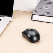Black computer mouse on a desk next to a laptop and notebook
