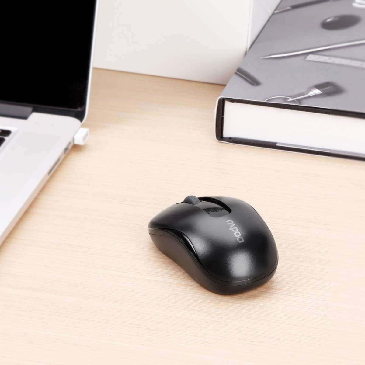 Black computer mouse on a desk next to a laptop and notebook